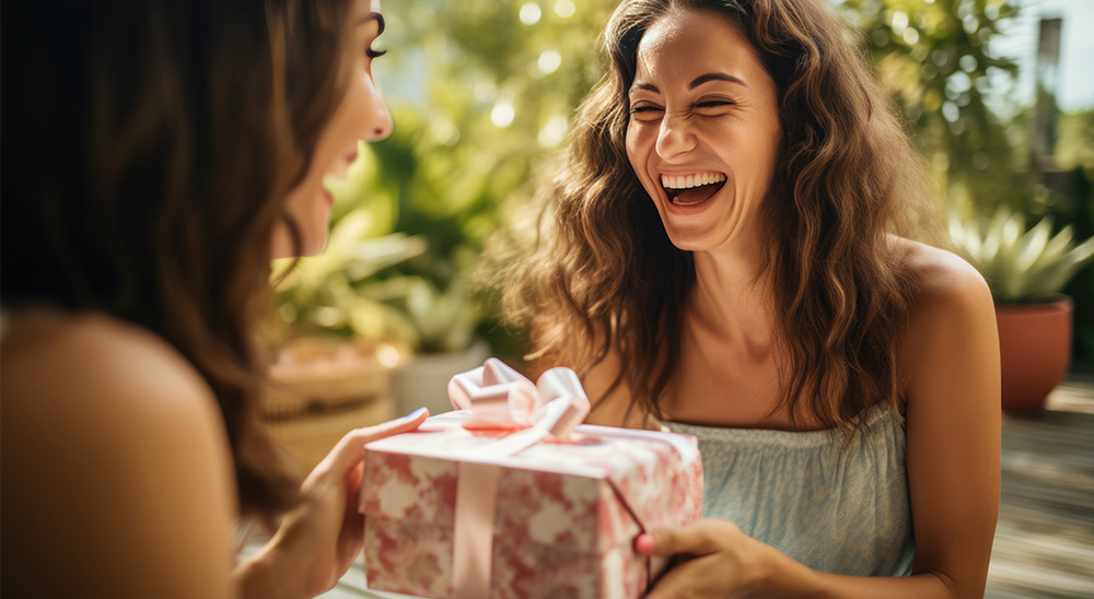 Besišypsanti moteris įteikia dovaną draugui.