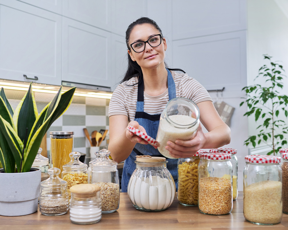 Moteris virtuvėje rodo indus sausam maistui laikyti