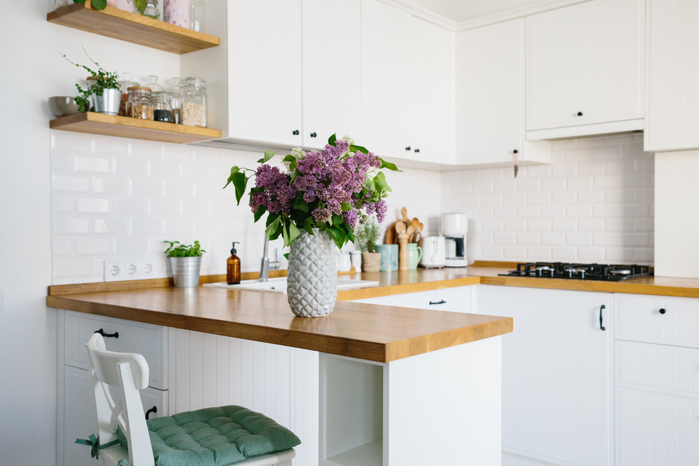 Nedidelė virtuvė su baltais skandinaviško stiliaus baldais