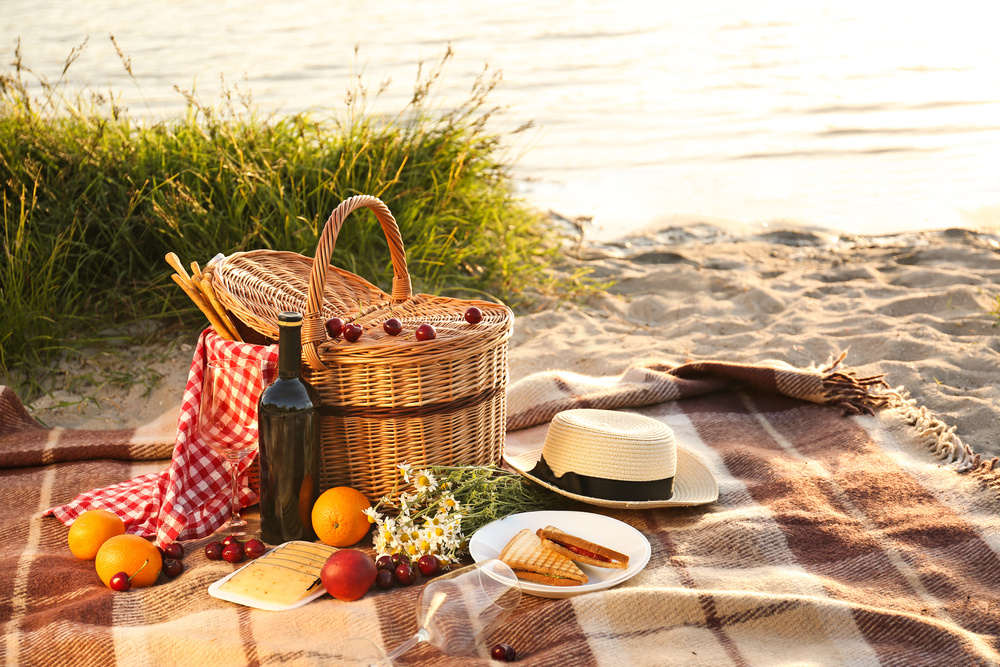 Iškylos krepšelis romantiškai vakarienei paplūdimyje prie upės