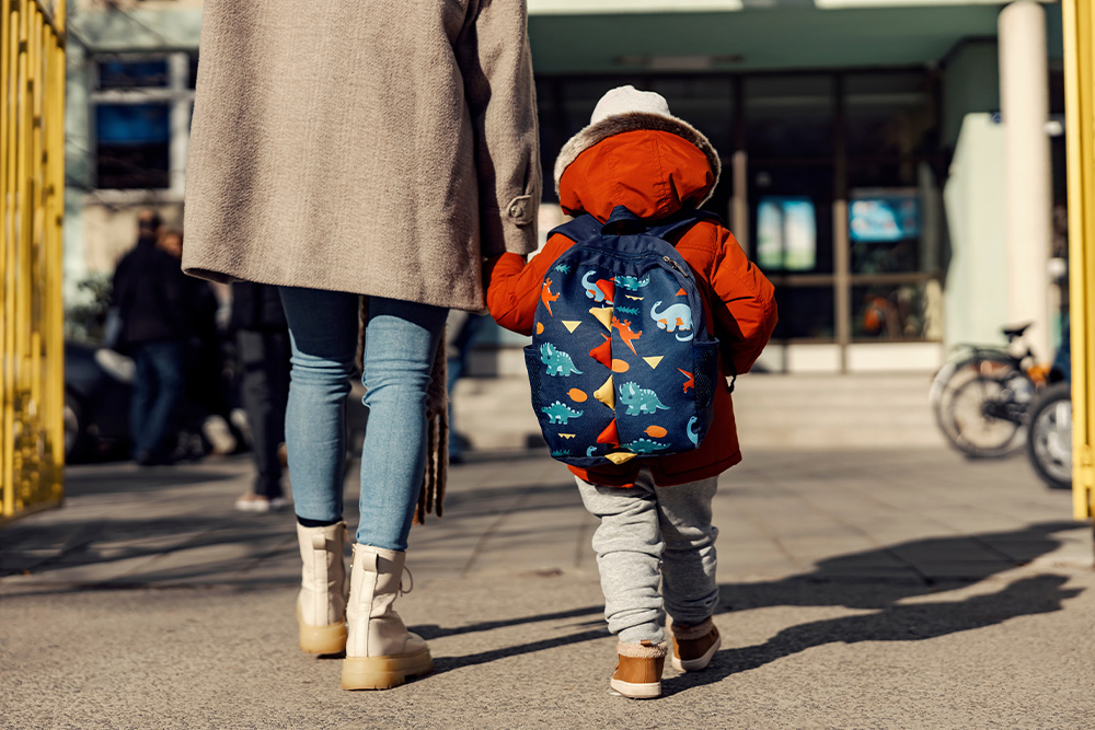 Mama veda už rankos darželinuką su kuprine 