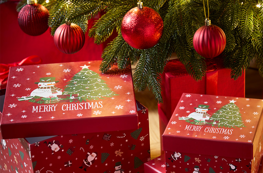 Dovanų dėžutės su Kalėdų motyvais prie Kalėdų eglutės.